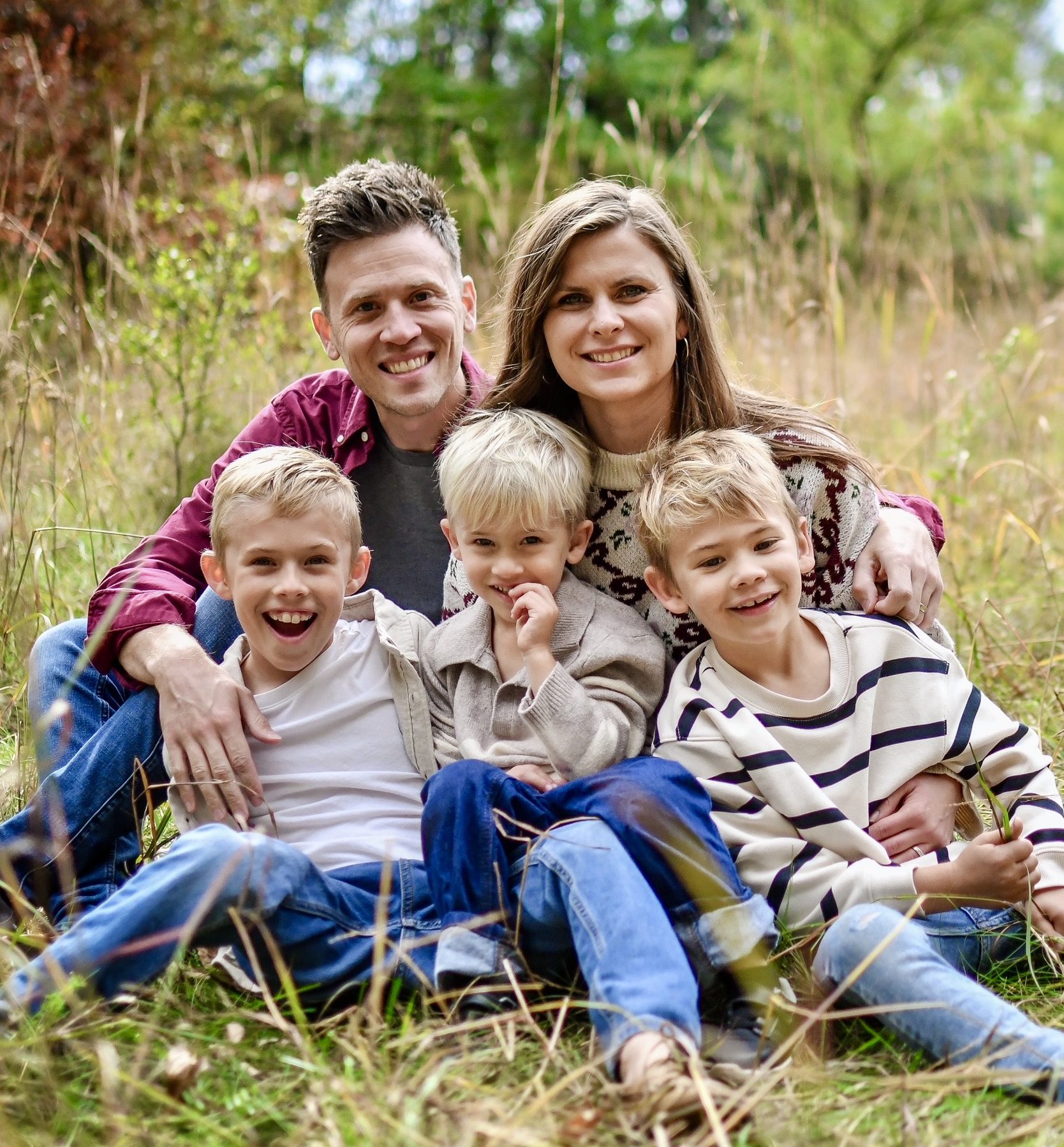family picture with two parents and three sons sitting in long grass - LoonShine Exterior Cleaning Services