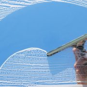 person cleaning a window with a squeegee - LoonShine Exterior Services professional residential window washing