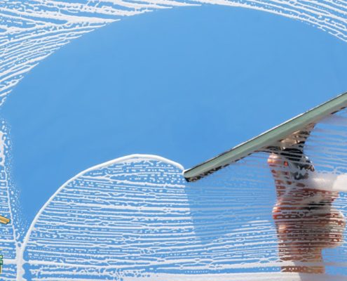 person cleaning a window with a squeegee - LoonShine Exterior Services professional residential window washing