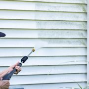 woman power washing the outside of her home - LoonShine Exterior Services safe siding cleaning methods
