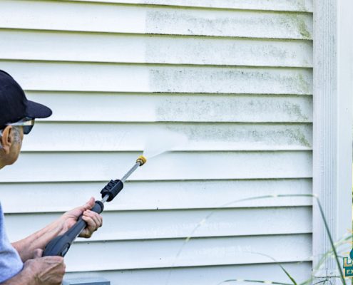 woman power washing the outside of her home - LoonShine Exterior Services safe siding cleaning methods