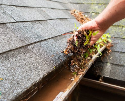 person scooping debris from gutters - LoonShine Exterior Services when should i schedule spring gutter cleaning for my house