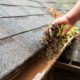 person scooping debris from gutters - LoonShine Exterior Services when should i schedule spring gutter cleaning for my house